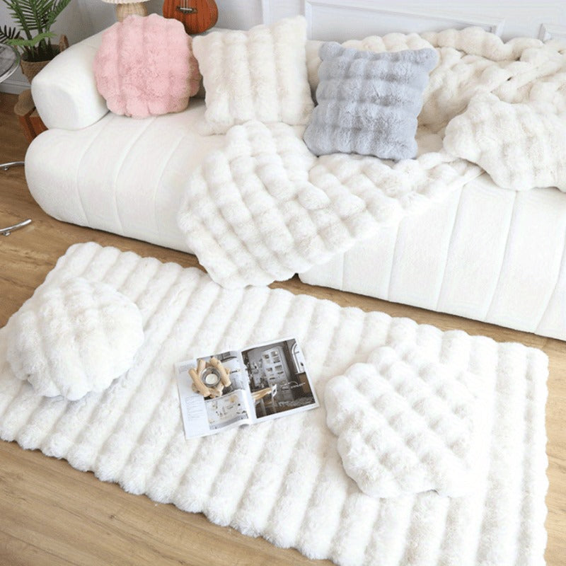 White plush bubble texture pillows and throw blanket on white sofa with matching fluffy rug on wooden floor