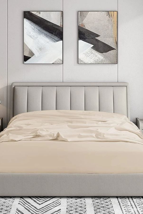Modern bedroom with beige upholstered bed, crumpled beige bedding, abstract black and white wall art