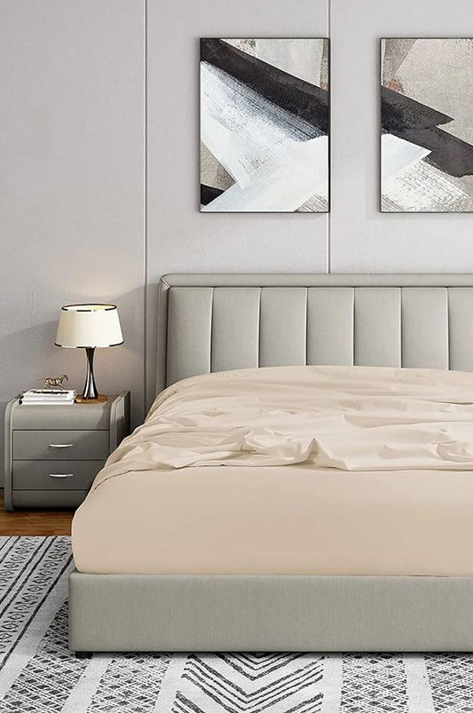Modern bedroom with tufted beige upholstered bed, abstract black and white wall art, gray nightstand, and table lamp