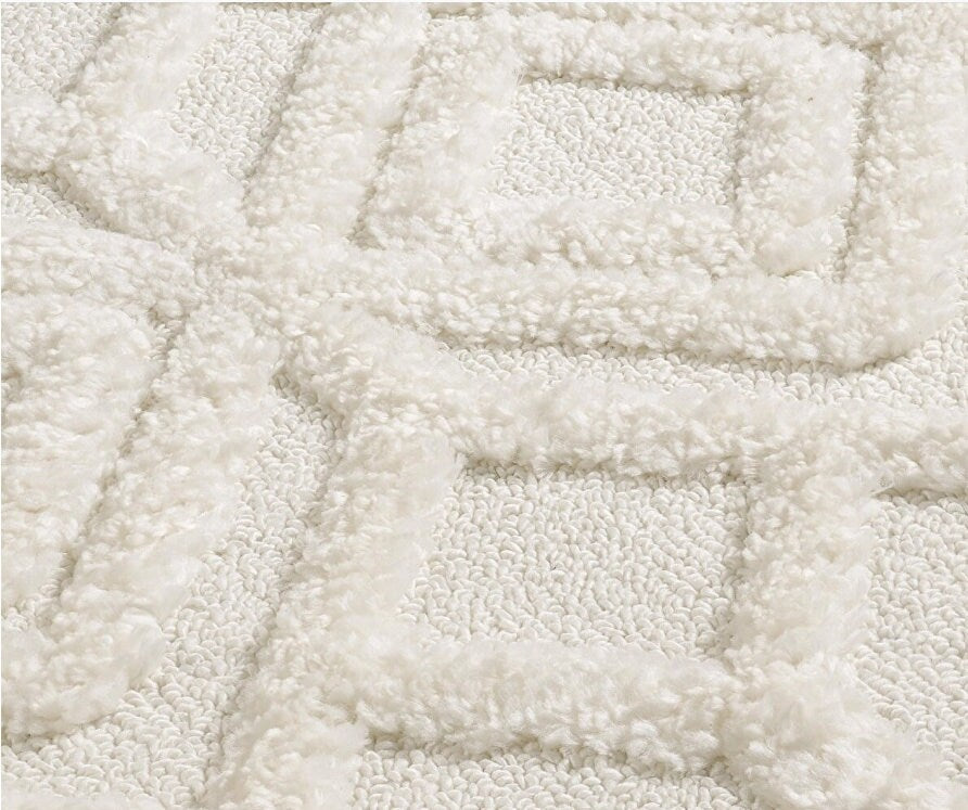 Close-up of white textured rug with geometric square patterns and soft, fluffy loops