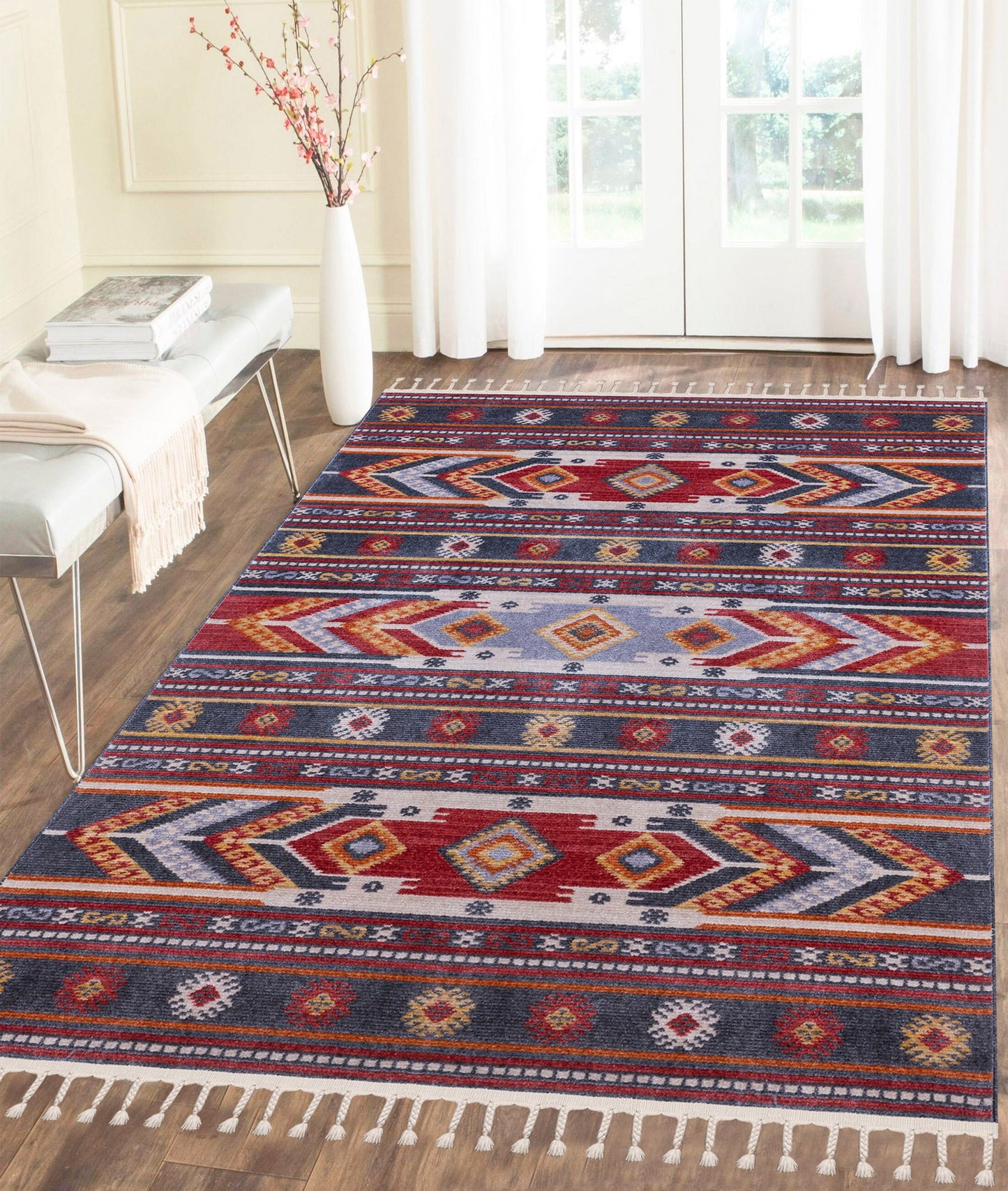 Colorful geometric patterned area rug with tassels in bright living room with wood floor and large windows