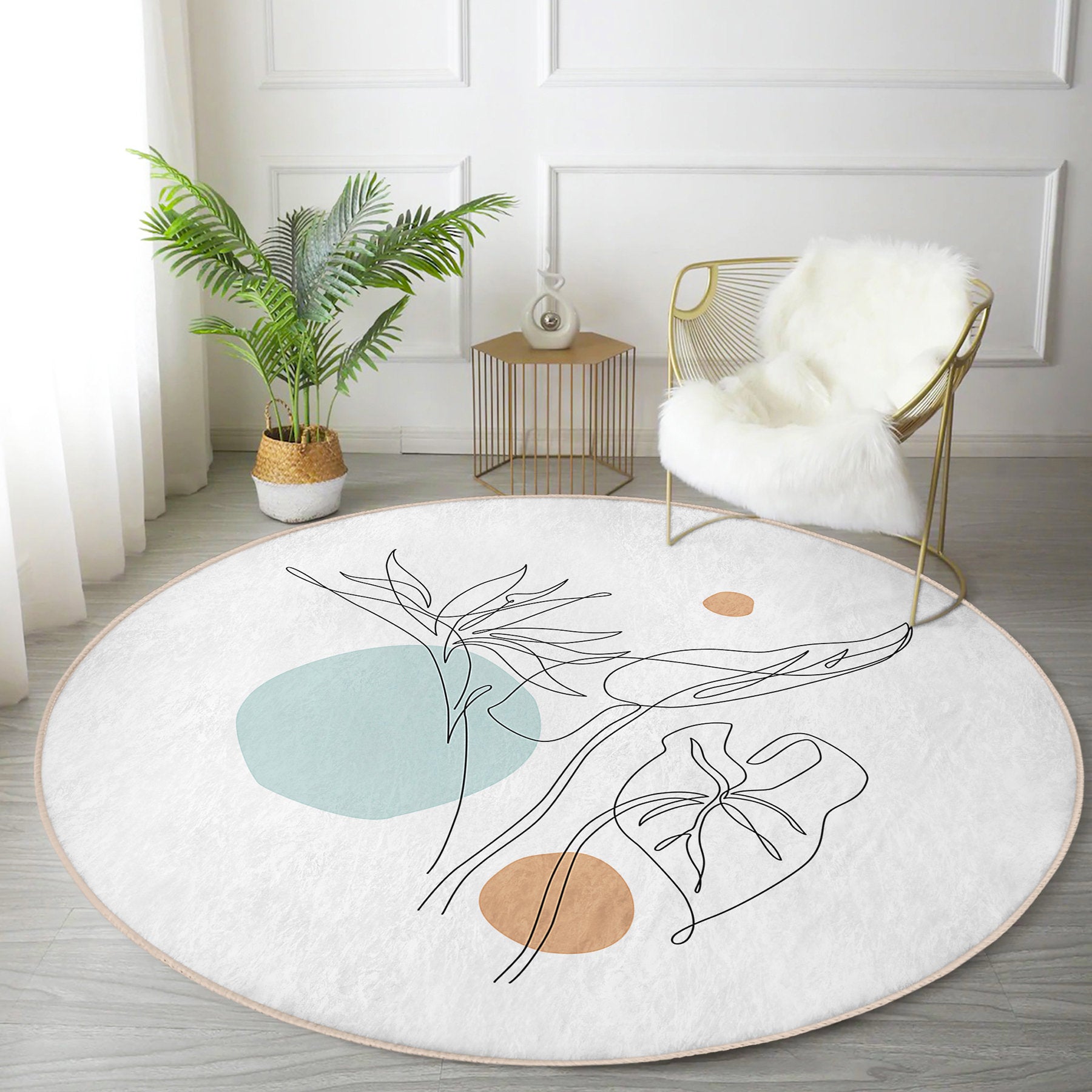 Modern living room with round white rug featuring abstract botanical design, gold wire chair with white fur throw, and potted plant