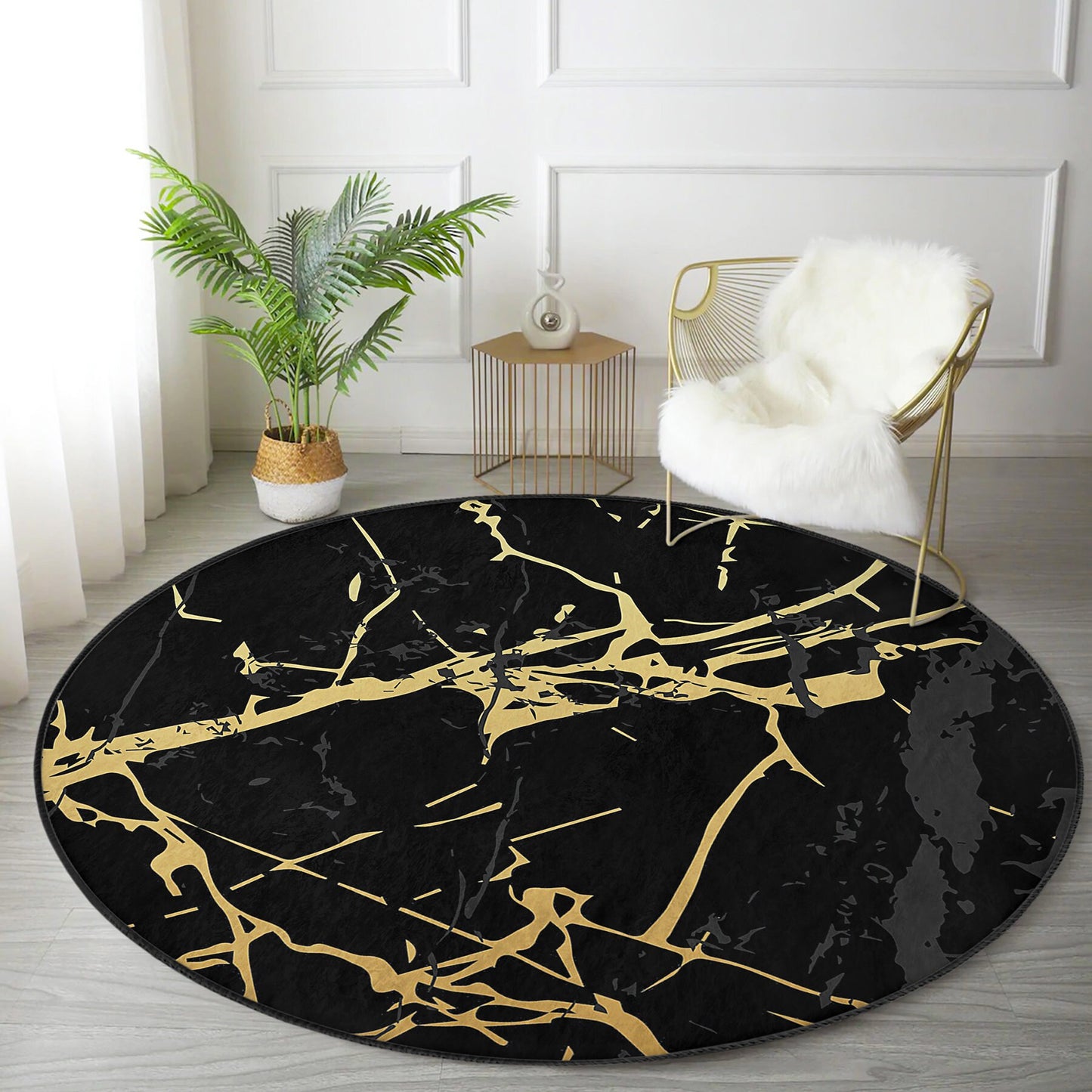 Round black rug with gold abstract marble pattern on light wood floor with gold chair and green potted plant