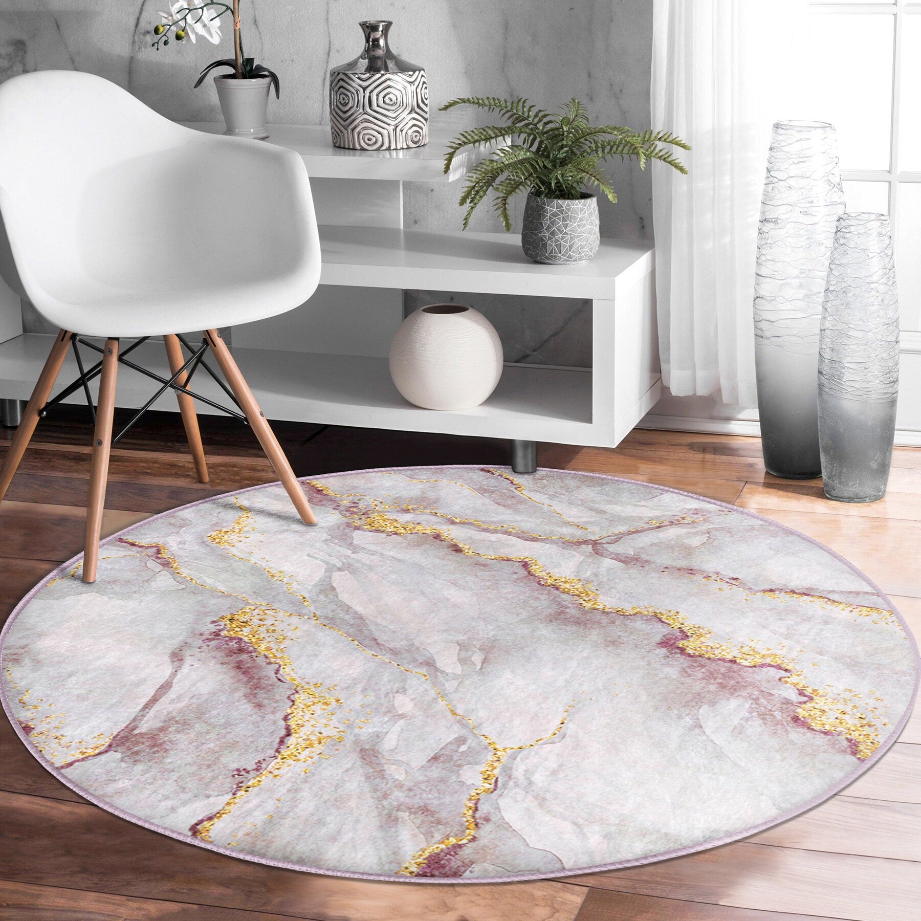 Modern white chair and white shelves with plants and vases on wooden floor with round marble-pattern rug