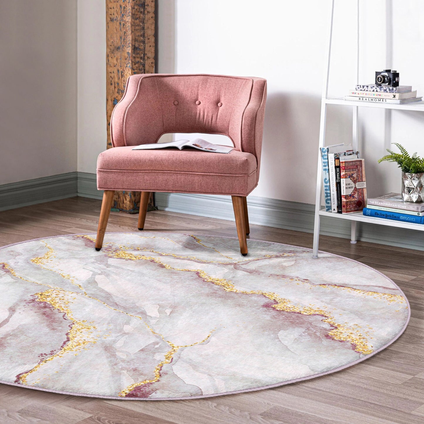 Pink upholstered accent chair on a round marble-patterned rug in a bright modern room with bookshelf