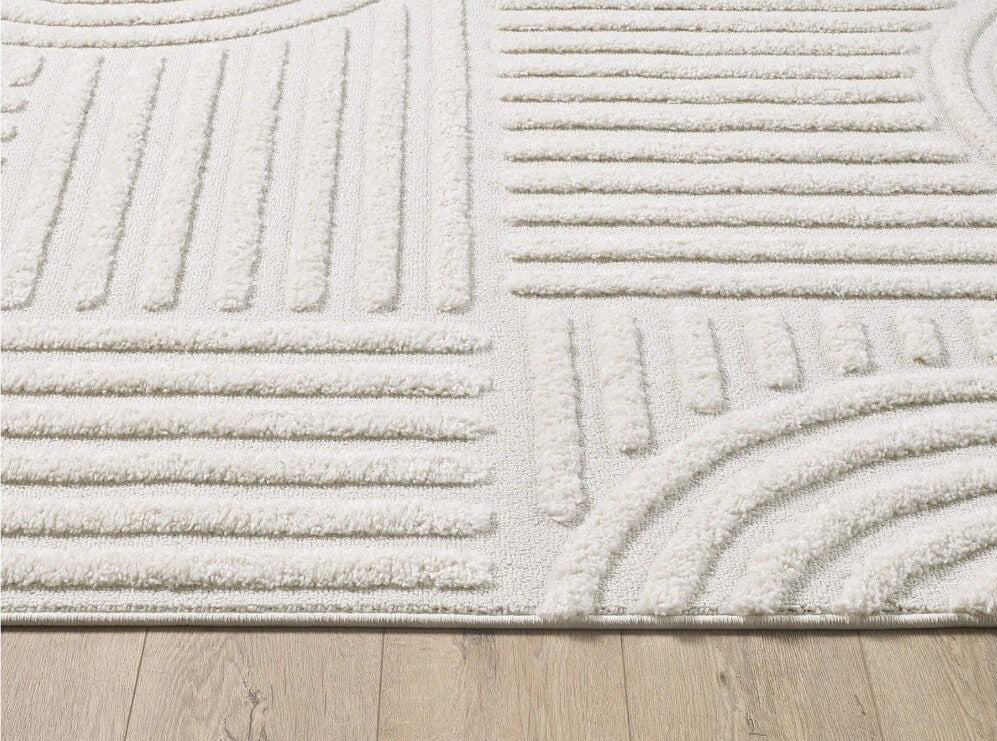 Close-up of white textured area rug with geometric patterns on light wood floor