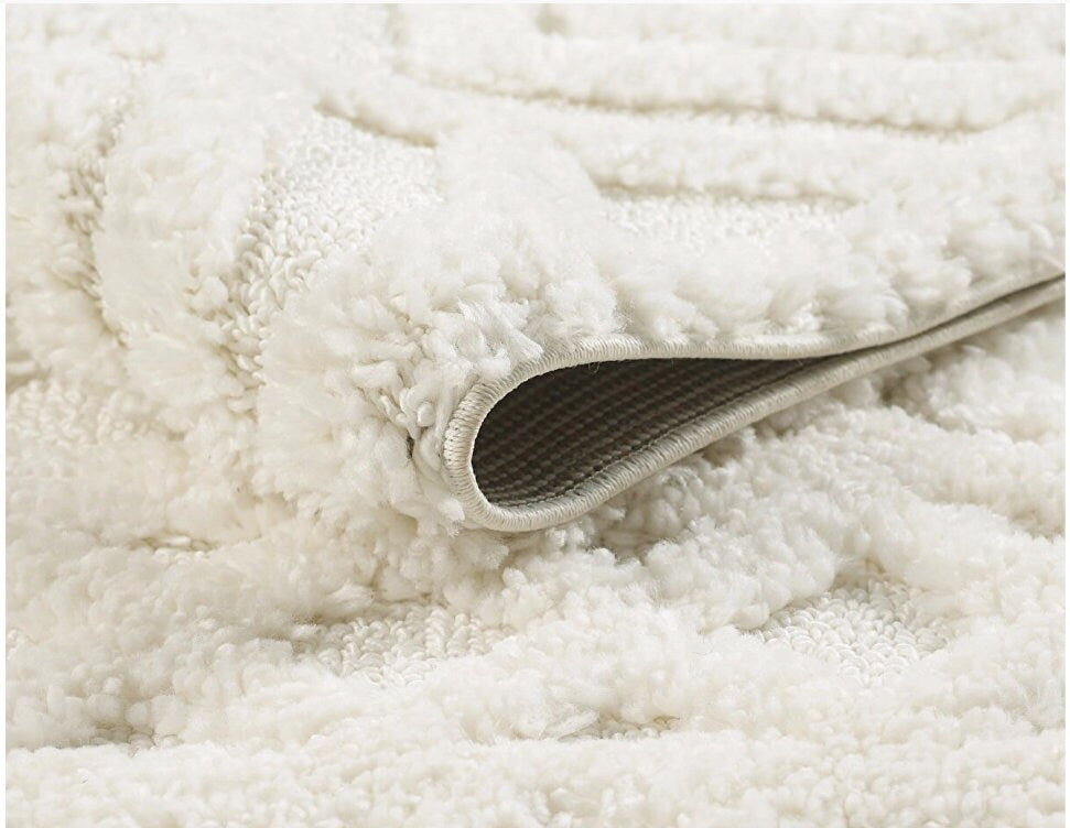 Close-up of soft white textured plush rug with folded edge showing non-slip backing