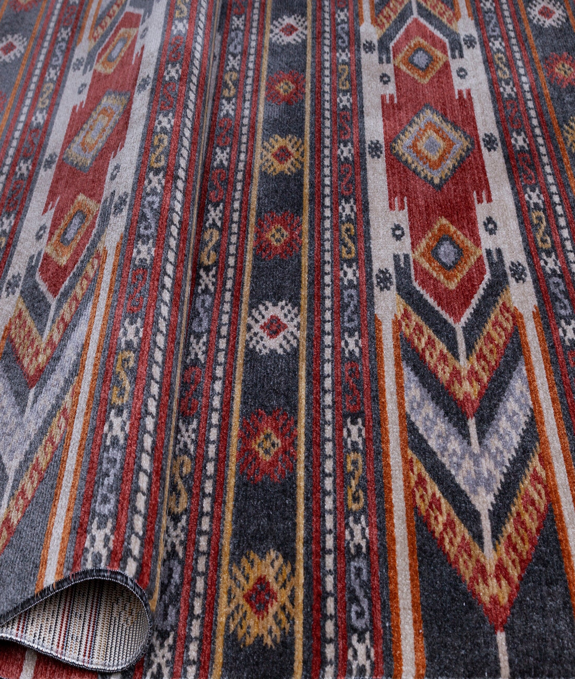 Close-up of a colorful ethnic patterned rug with red, gray, yellow, and orange geometric designs