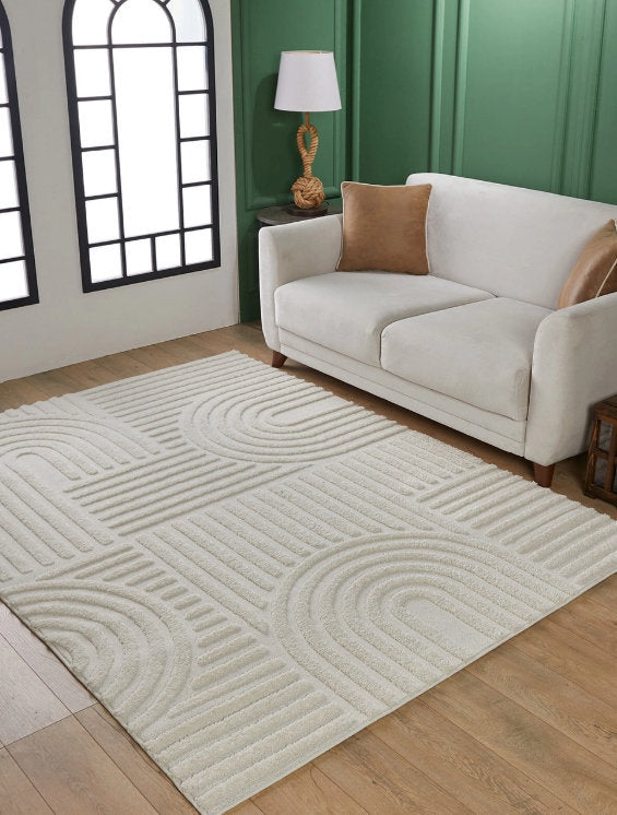 Modern living room with beige sofa, brown pillows, white textured geometric rug, wood floor and green paneled wall