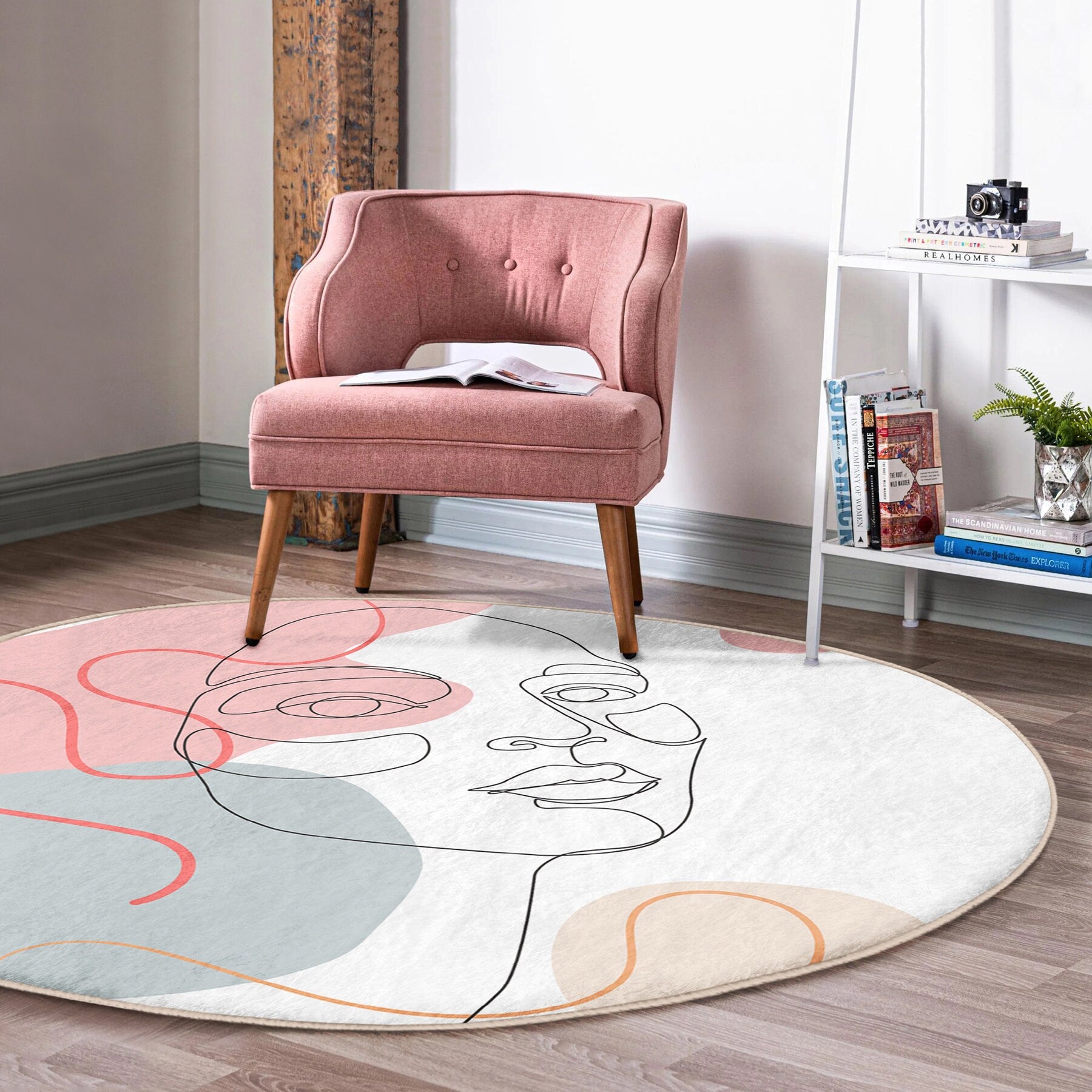 Pink upholstered accent chair with wooden legs on round modern rug with abstract face design in stylish living room
