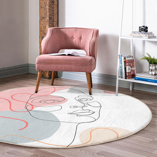Pink upholstered accent chair with wooden legs on round modern rug with abstract face design in stylish living room